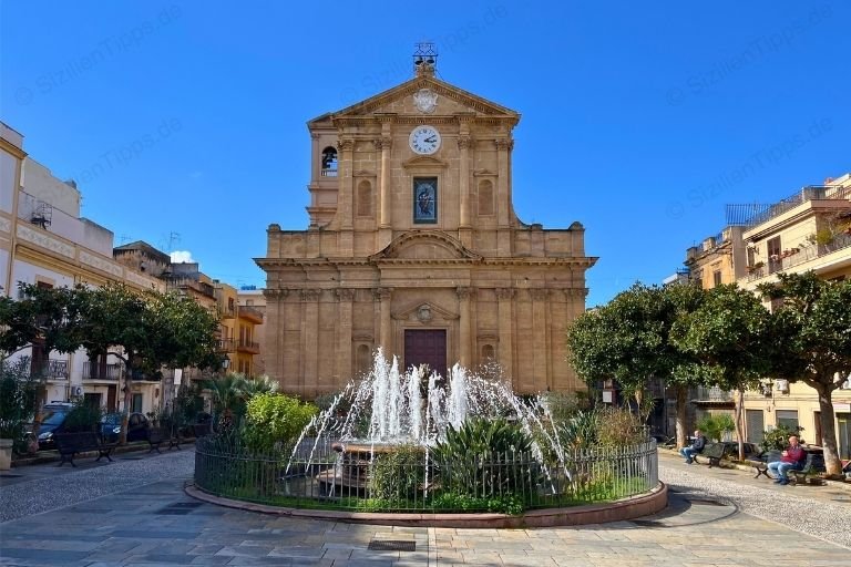 Ein Springbrunnen vor einer Kirche unter blauem Himmel
