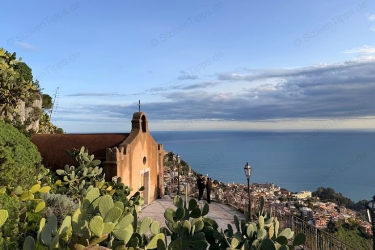 Eine Kirche thront über einem Dorf am Meer