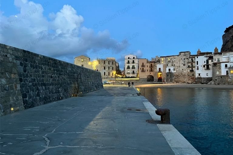 DIe Hafenmauer und Wohnhäuser in Cefalù bei Sonnenuntergang