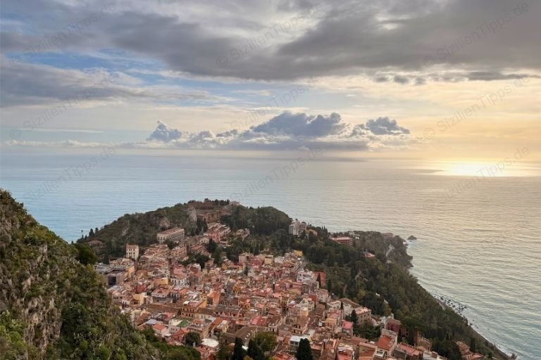 Häuser auf einem Hügel über dem Meer bei Sonnenaufgang