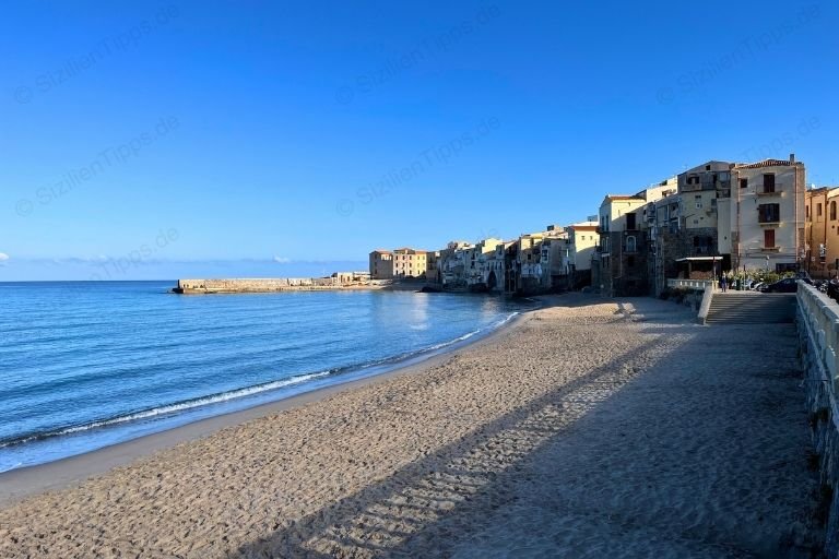 Ein Sandstrand vor Häuserfronten in Cefalù