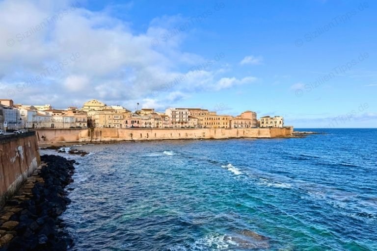 Blauer Himmel, kleine Wellen und bunte Häuser an der Promenade von Syrakus