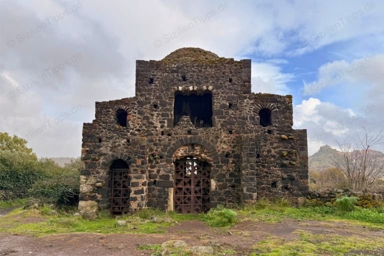 Eine alte Kirche umgeben von Gras und Sträuchern