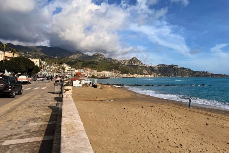 Meer, Strand und eine Straße vor Bergen