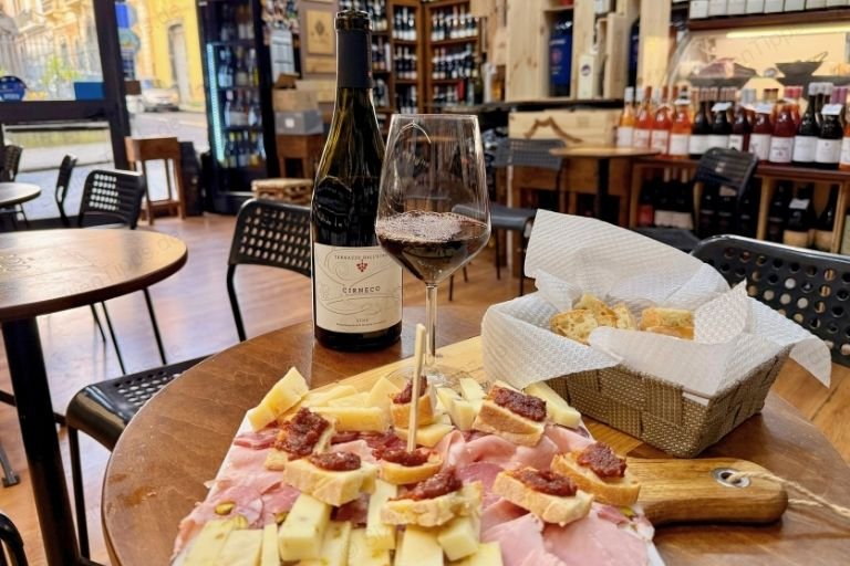 Ein Glas Rotwein und eine Platte mit Wurst und Käse 